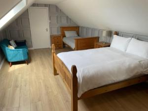 a bedroom with a large bed and a chair at Newhall Cottage in Bressay