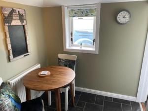 ein Esszimmer mit einem Holztisch und einem Fenster in der Unterkunft Newhall Cottage in Bressay + 11 Fotos