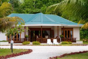 a house with a blue roof and white chairs at Les Villas D'or in Baie Sainte Anne