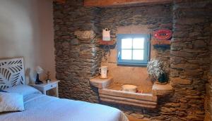 1 dormitorio con pared de piedra, cama y ventana en Apartamento con Wifi en Ossèja en Osséja
