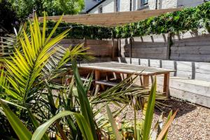 a wooden picnic table in a garden with plants at 4 The Old Schoolhouse: Parking, hot tub, garden, air con in Whitstable