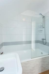 a bathroom with a shower and a white tub at 4 The Old Schoolhouse: Parking, hot tub, garden, air con in Whitstable +56 photos