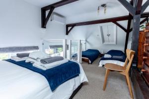 a bedroom with two beds and a chair in it at 4 The Old Schoolhouse: Parking, hot tub, garden, air con in Whitstable
