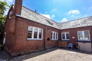 a brick house with a garage and a building at 4 The Old Schoolhouse: Parking, hot tub, garden, air con in Whitstable