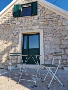 dwa krzesła i stół przed budynkiem w obiekcie House Riva w mieście Pirovac