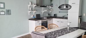 una cocina con armarios blancos y una mesa con sillas. en Lotta's Ferienhäuschen, en Emden