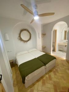 Doñana Suite Casa-Hotel في إل روثيو: غرفة نوم بسرير ومروحة سقف