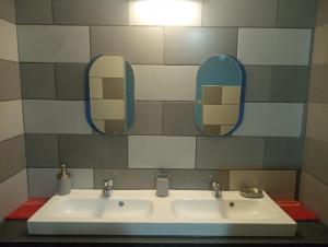 a bathroom with a sink and two mirrors at Couleur pastel in Saint-Louis