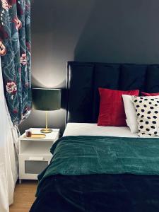 a bedroom with a bed with red pillows and a lamp at Studio 5 apartman in Kragujevac +26 photos