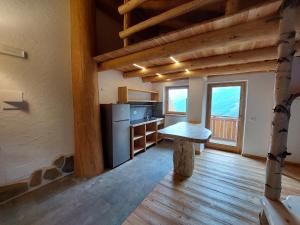 eine Küche mit einem Kühlschrank und einem Tisch im Zimmer in der Unterkunft Agriturismo Malga Pontevecchio in Cogolo