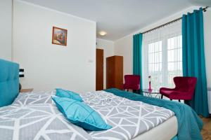 a bedroom with a bed and two red chairs at Pokoje Gościnne IDALIA - Blisko Plaży Komfort i Wygoda in Karwia
