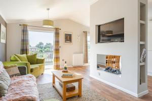 sala de estar con sofá y chimenea en Heathland Lodge - Norfolk Cottage Agency, en Kelling