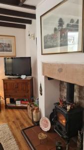 a living room with a fireplace and a television at Peaceful cottage retreat in the Peak District in Wirksworth