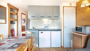 a small kitchen with a refrigerator and a table at V du Bachat Asters B21 - Appt 6 pers in Chamrousse