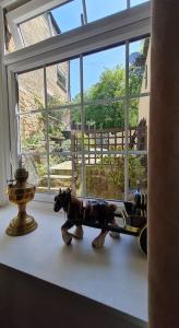 Un cheval jouet est assis sur un rebord de fenêtre dans l'établissement Peaceful cottage retreat in the Peak District, à Wirksworth