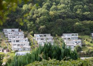 a row of houses on a hill with trees at Millendreath Beach Resort in Looe