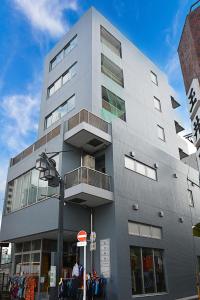 a tall gray building with a balcony on a street at illi Sun Shimokitazawa in Tokyo