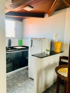 a kitchen with a white refrigerator and a table at Flet vista mar 1 in Arraial do Cabo