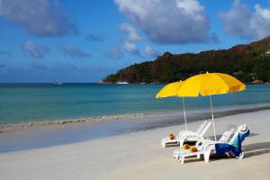 two chairs and an umbrella on a beach at Les Villas D'or in Baie Sainte Anne