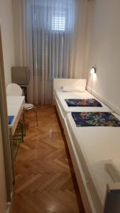 two beds in a room with a table and a chair at Rooms Aida in Pula