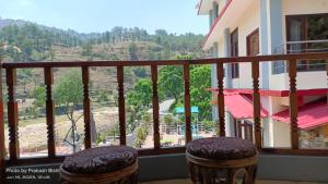 a balcony with two stools and a view of a mountain at Shivalik River Retreat in Almora