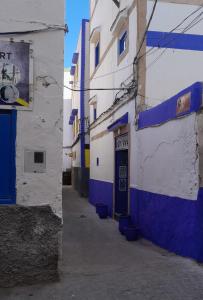 an alley with blue and white buildings and a door at Wave Mogador in Essaouira