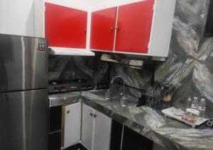 La cuisine est équipée de placards rouges et d'un réfrigérateur en acier inoxydable. dans l'établissement King Rapid Rise Hotel, à Ángeles