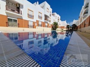 a swimming pool in front of a building at Pé na Areia in Cabanas de Tavira