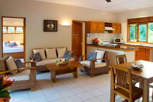 ein Wohnzimmer mit Sofas und Stühlen sowie eine Küche in der Unterkunft Les Villas D'or in Baie Sainte Anne