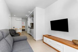 sala de estar con sofá y TV en la pared en Tokai Beach Residences, en San Pedro del Pinatar
