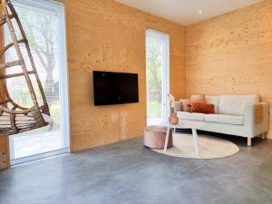 een woonkamer met een bank en een tv aan de muur bij Vakantiewoning Studio 51 OK49 in Oostkapelle