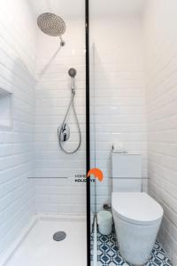 La salle de bains blanche est pourvue d'une douche et de toilettes. dans l'établissement #063 Beach Flat with Sea View Balcony, AC, à Albufeira