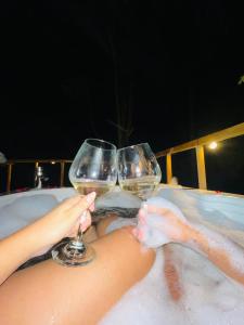 dos personas sosteniendo copas de vino en una bañera en Cabaña Los Cedros, en La Vega
