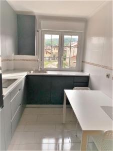 a white kitchen with a table and a window at Apartamentos Del Pisuerga in Cervera de Pisuerga