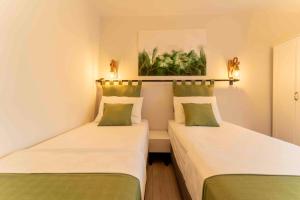 two beds in a small room with green and white at Kamkat Otel in Kemer