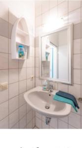 a white bathroom with a sink and a mirror at Wuppertal-Ronsdorf Ferienwohnung Appartement für 1-2 in Erbschlö