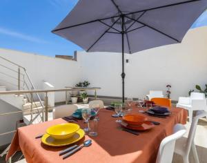 a dining table with an umbrella on a balcony at Casa da Madou in Setúbal