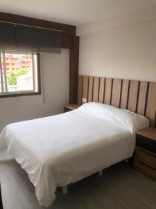 Un dormitorio con una gran cama blanca y una ventana en Piso Negreira, en Negreira