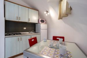 a small kitchen with a table and red chairs at 3 Sirene Sciacca Fronte Mare in Sciacca