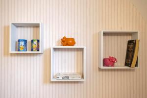 two white shelves on a wall with books and toys at 3 Sirene Sciacca Fronte Mare in Sciacca