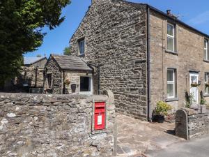 an old stone house with a red door and a stone wall at Rose Cottage in Settle
