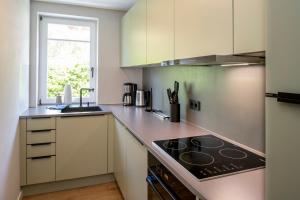 uma cozinha com armários brancos e um forno com placa de fogão em Ferienhaus Seeschwalbe 12 2 em Langeoog