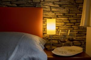 two glasses of wine on a table next to a bed at 3 Sirene Sciacca Fronte Mare in Sciacca