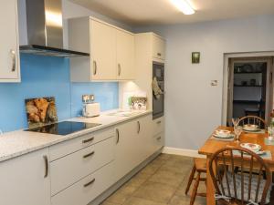 a kitchen with white cabinets and a wooden table at Rose Cottage in Settle