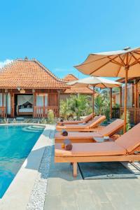 una piscina con diversi tavoli e ombrelloni accanto a una casa di SUNSHINE VILLAS UBUD ad Ubud