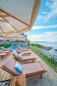 a row of tables and chairs on a balcony with the ocean at DOLPHIN BAY BOUTIQUE COMPLEX Sozopol in Sozopol