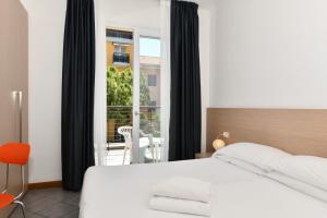 1 dormitorio con cama blanca y balcón en Hotel Eden, en Lido di Jesolo