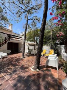 un patio con mesa y 2 árboles y sillas en Villa típica ideal para as suas férias em família! en Monte Gordo