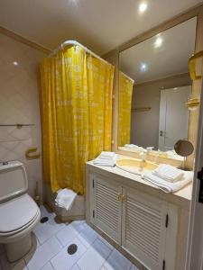 baño con aseo y cortina de ducha amarilla en Villa típica ideal para as suas férias em família! en Monte Gordo