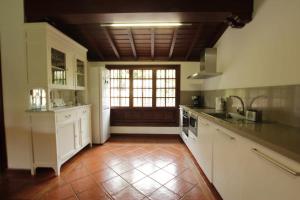 une grande cuisine avec des placards blancs et une fenêtre dans l'établissement Casa privada con piscinajacuzzi en La Orotava, à La Orotava